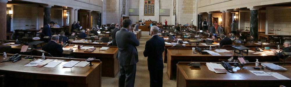 A photograph of two state senators overlooking the entrance to the George W. Norris Legislative Chamber.