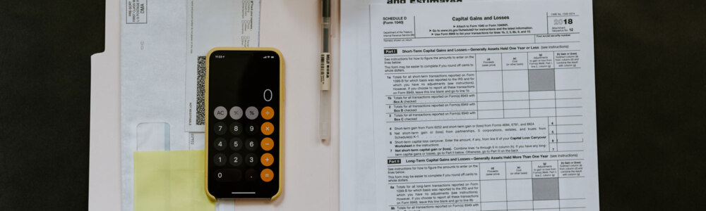 A folder containing tax documents and a cell phone opened to the calculator app